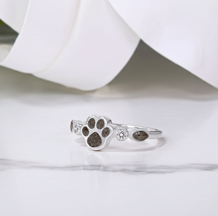Anillo de plata con huella de perro rellena de cenizas de mascota y circonitas a los lados