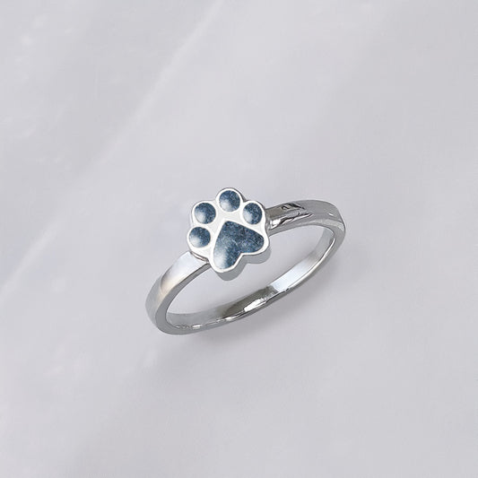 Anillo de plata con cenizas de mascota en una huella de perro o gato o mascota.