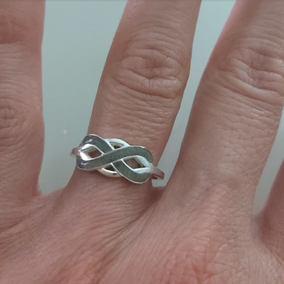 Anillo de plata con cenizas en mano de mujer.