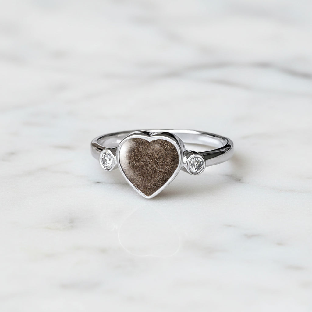 Anillo con pelo de perro, gato o mascota dentro de corazón de plata con dos circonitas.