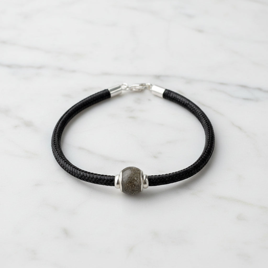 Charm con cenizas y ojales de plata dentro de pulsera de cuero