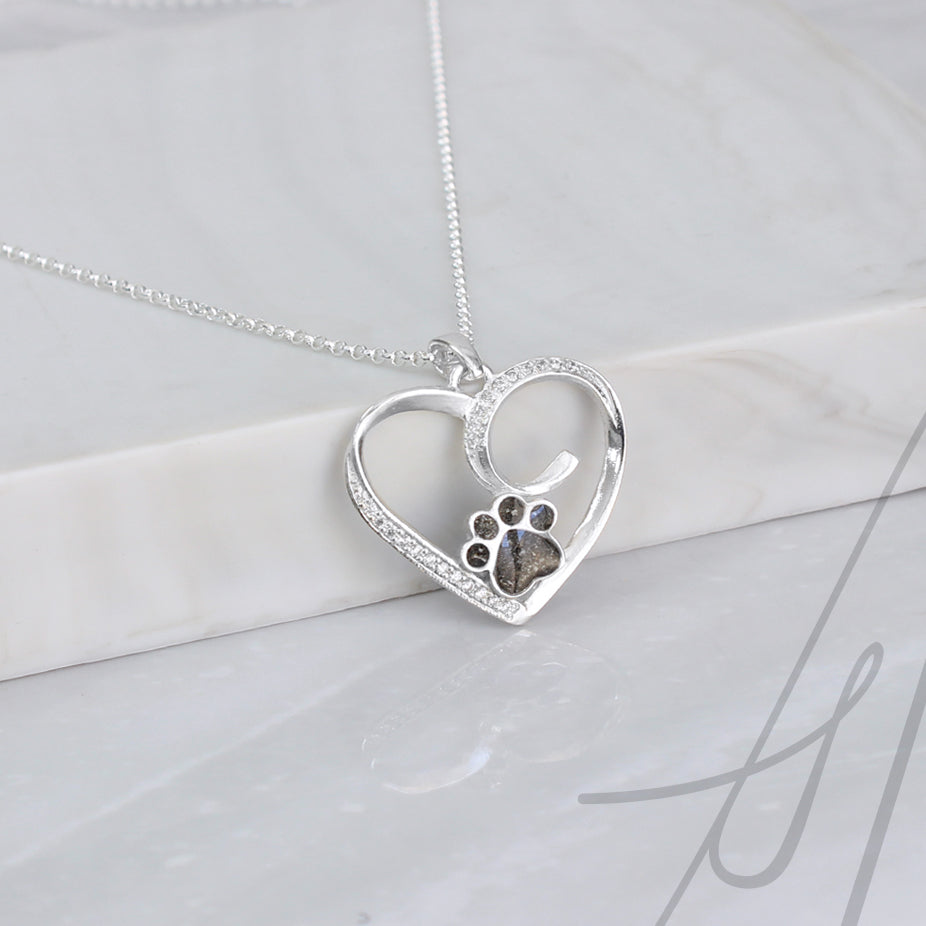 Colgante con cenizas de tu mascota dentro de una huella custodiada por un corazón de plata rodeado de circonitas.