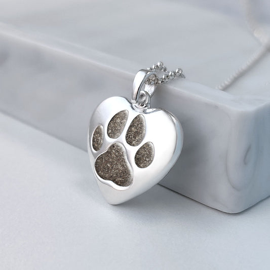 Colgante de plata con cenizas de mascota dentro de huella incrustada.