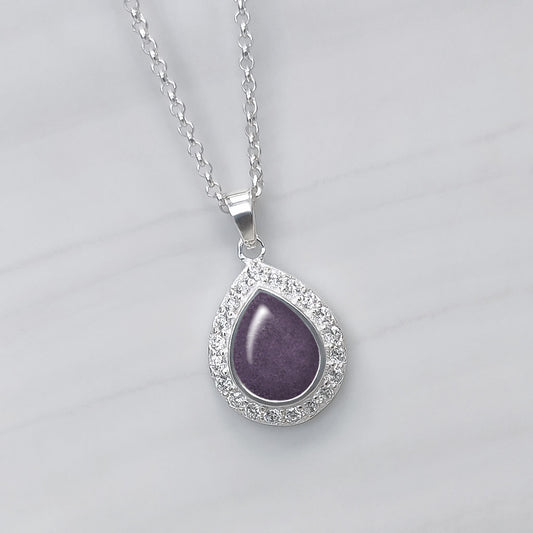 Colgante con cenizas de mascota en lágrima o perla de plata con circonitas alrededor. Color morado.