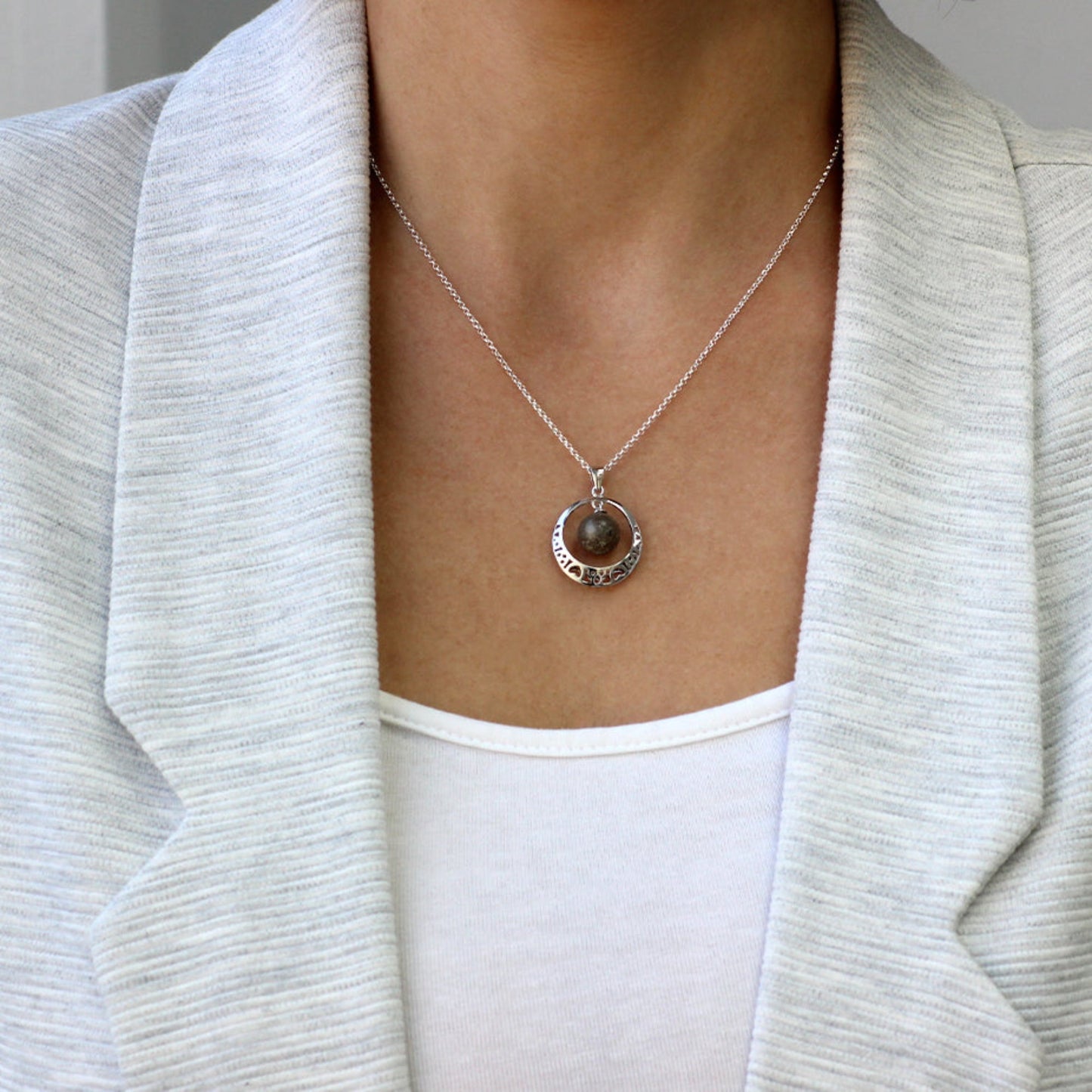 Colgante de plata con cenizas en esfera dentro de aro con corazones.