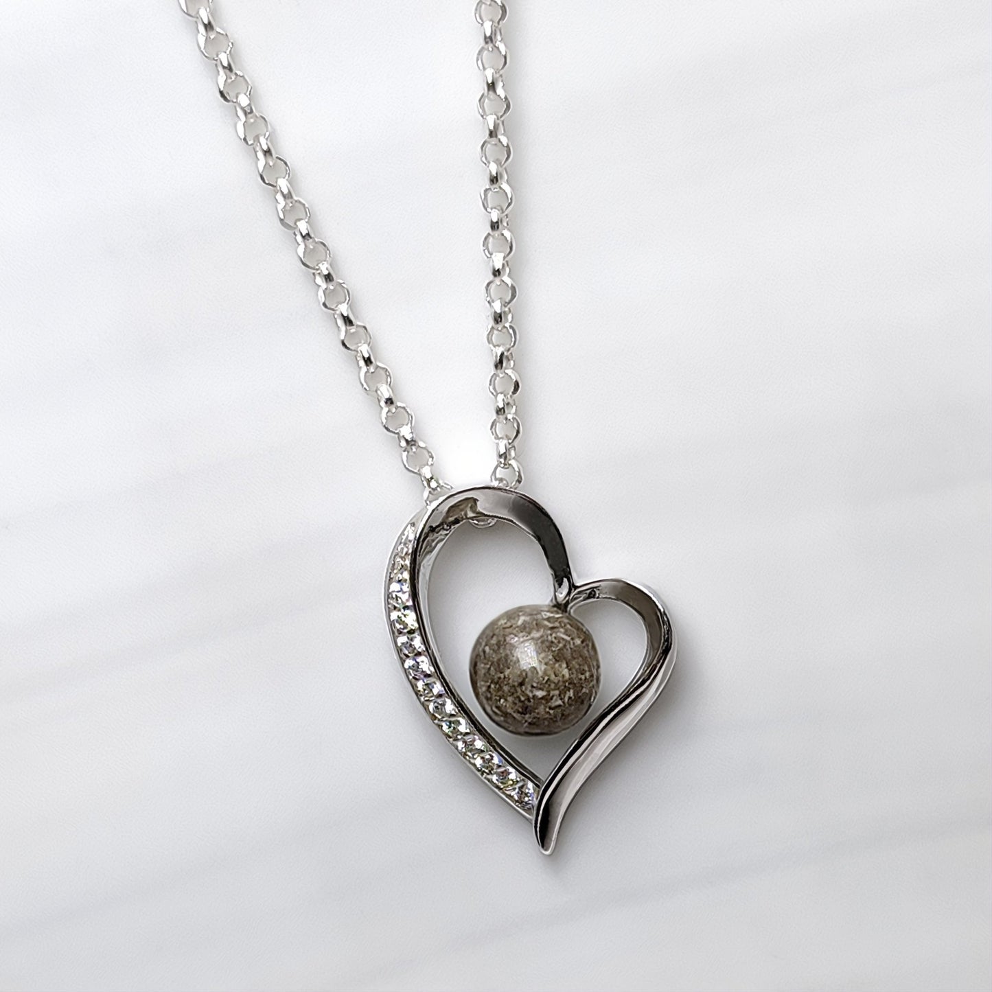 Colgante con cenizas dentro de un corazón de plata con circonitas