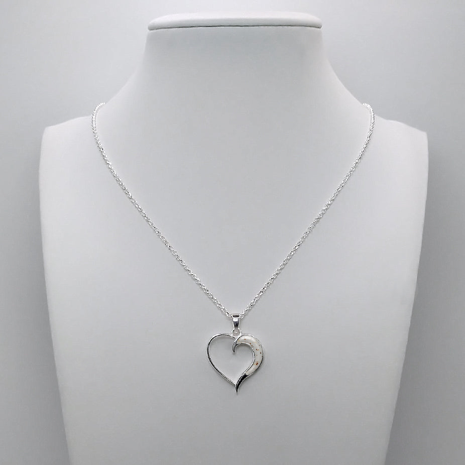 Colgante de plata con partículas de cordón umbilical en forma de luna dentro de corazón.