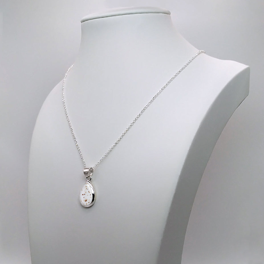 Colgante de plata con partículas de cordón umbilical dentro de bisel en forma de lágrima, gota o perla.