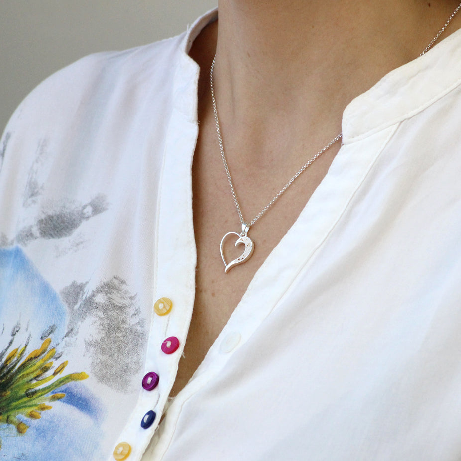 Colgante de plata con cordón umbilical en un lateral de corazón.