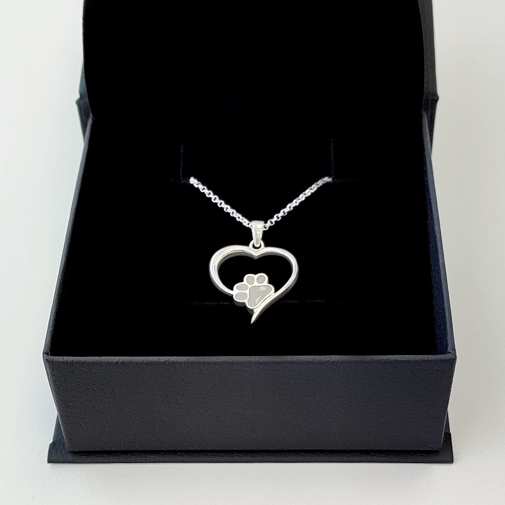 Colgante de plata con pelo de perro o gato dentro de corazón.