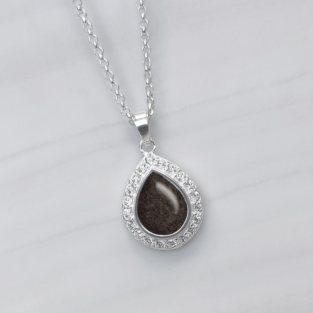 Colgante de plata y circonitas con una gema central en forma de lágrima o perla que contiene pelo de tu mascota.