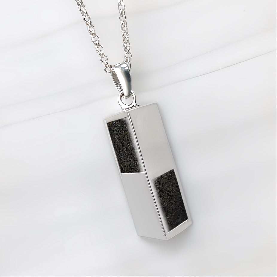 Colgante de plata con forma de prisma que contiene arena o tierra de una o de dos playas.