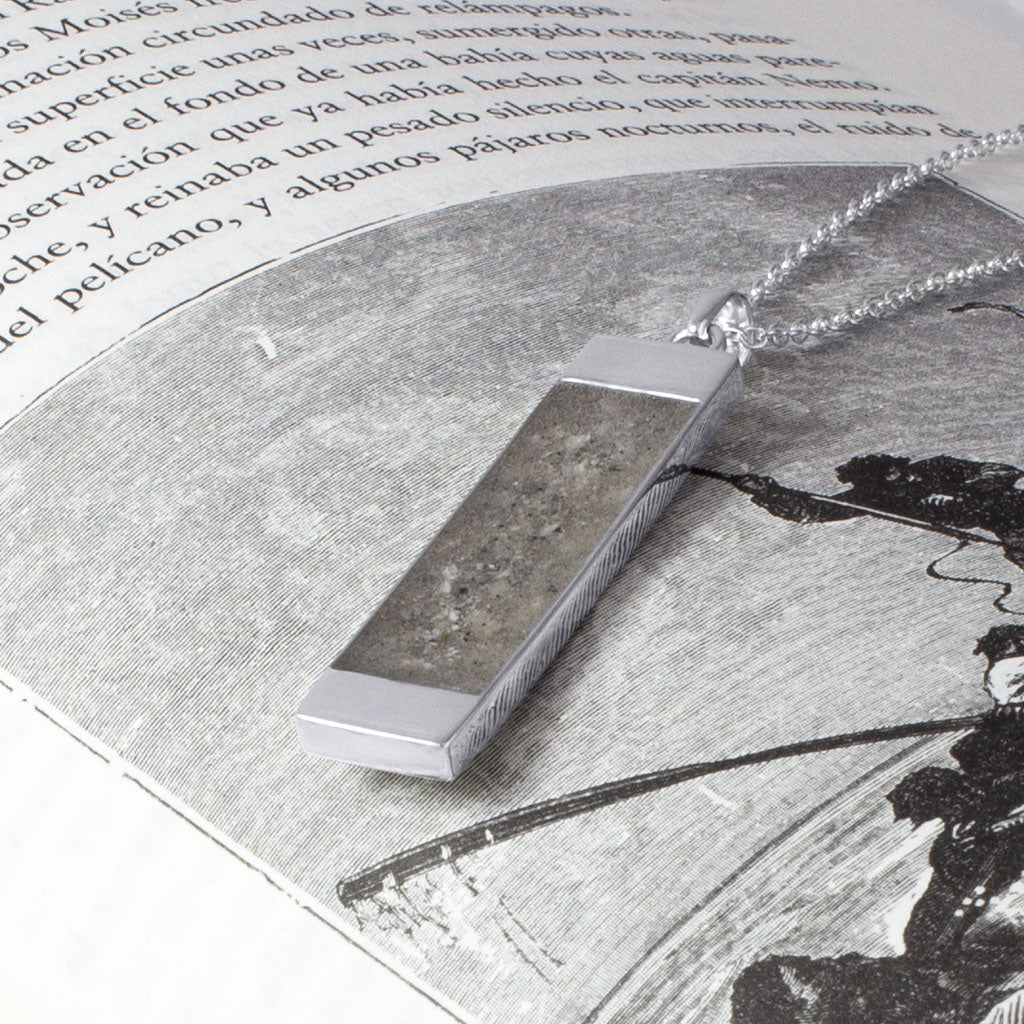 Colgante rectangular en plata con cenizas en su interior.