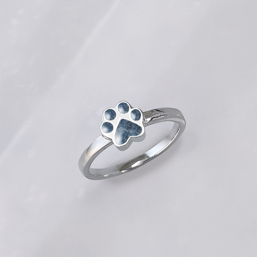 Anillo de plata con cenizas de mascota en una huella de perro o gato o mascota.