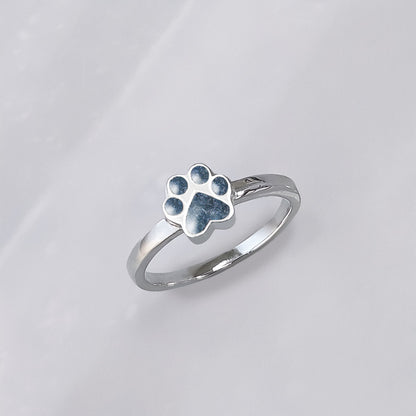 Anillo de plata con cenizas de mascota en una huella de perro o gato o mascota.