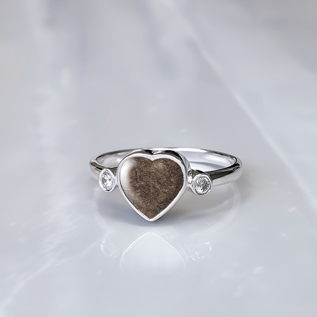 Anillo con pelo de perro, gato o mascota dentro de corazón de plata con dos circonitas.