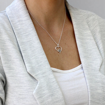 Colgante de plata con cenizas de mascota dentro de huella en corazón.