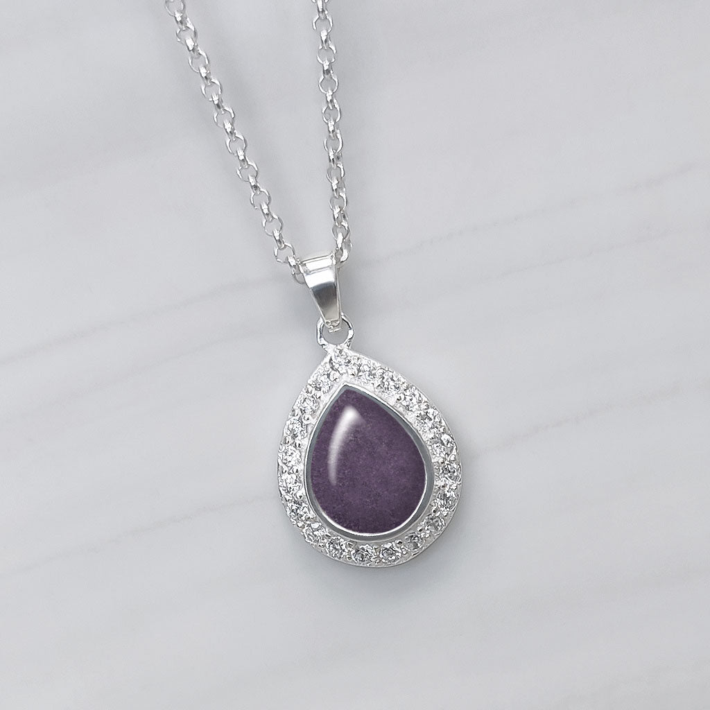 Colgante con cenizas de mascota en lágrima o perla de plata con circonitas alrededor. Color morado. 