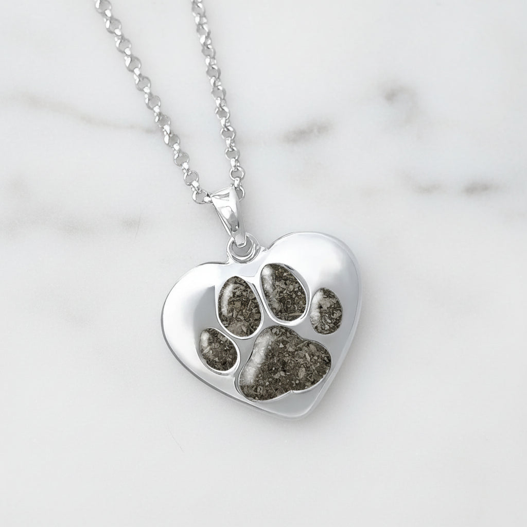 Colgante de plata con cenizas de mascota dentro de huella incrustada.