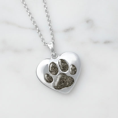 Colgante de plata con cenizas de mascota dentro de huella incrustada.